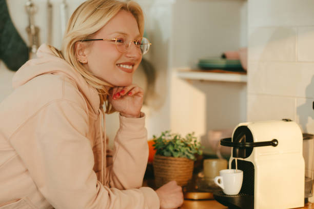 istock A happy blond woman is making fresh coffee on a coffee machine at home. 1520622045