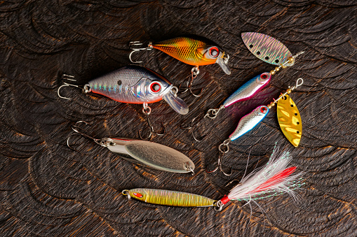 Set of metal and plastic lures for fishing on dark oak surface