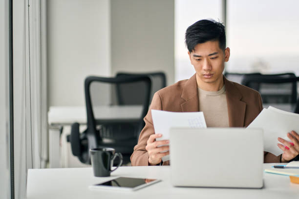 istock Serious Asian business man checking corporate financial documents in office. 1520623962