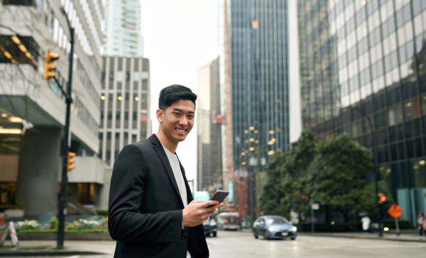 istock Young Asian business man professional standing in city using phone. Vertical 1520624235