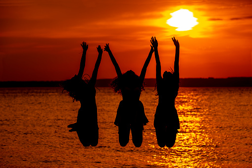 silhouette of three girlfriends on the beach