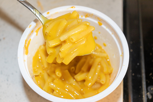 Spoonful of macaroni and cheese in white bowl and kitchen counter background. Taken in Toronto, Canada.