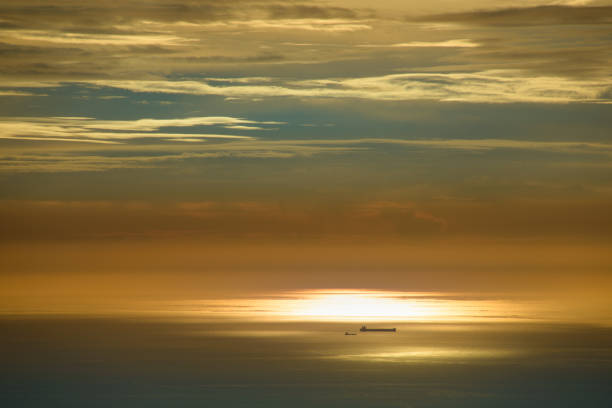 The sky and sea are orange and gold. Ships and dynamic clouds. At dusk, the scenery of the seaside in Miaoli County.