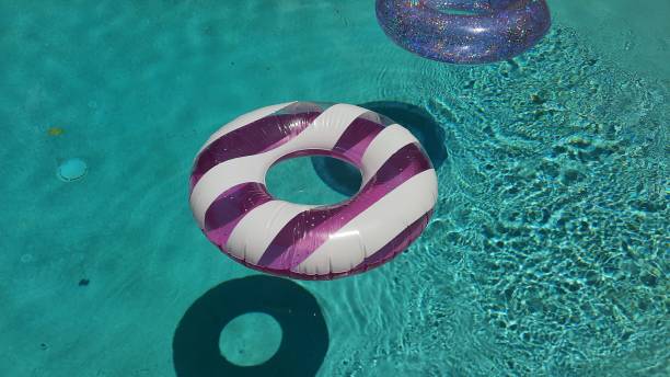 istock Pink and white stripped doughnut shaped floater on a turquoise water pool 1520882242
