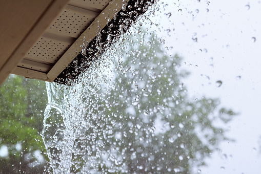 During downpour, water escapes from over gutters.