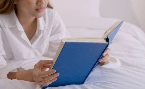istock Young woman reading book on bed at home. 1520920476