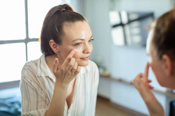 istock Young woman putting on makeup while looking in a mirror at home 1520979711