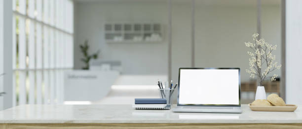 A modern workspace in a modern white room with a laptop white screen mockup stock photo