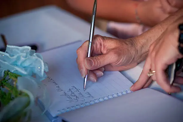 horizontal image of someone signing a guestbook at a wedding