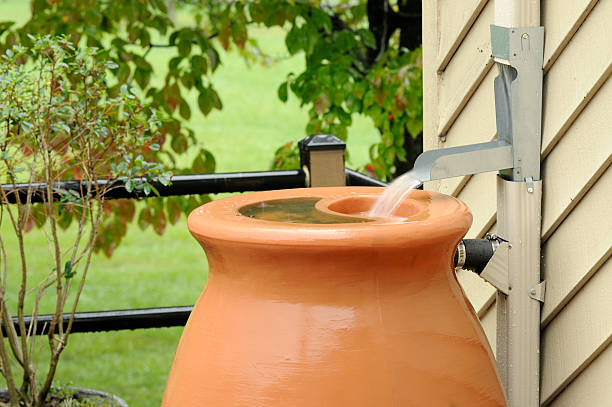 A tan rain barrel outside a home stock photo