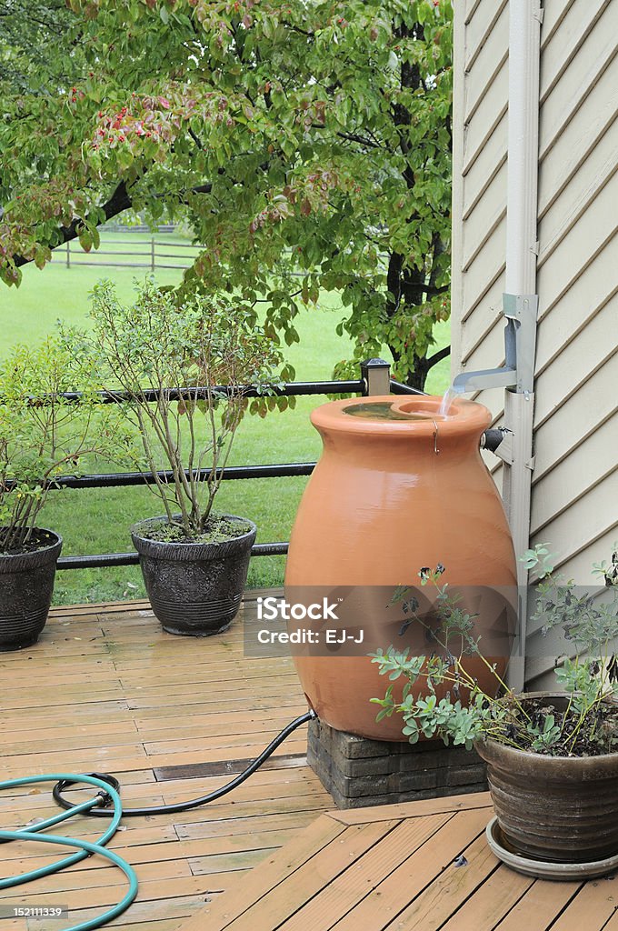 Rain Barrel Rain barrel being used to capture water from house gutters.  Water is pouring into barrel during rain storm. Barrel Stock Photo