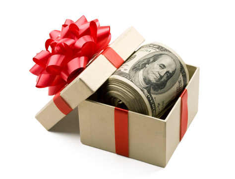 A roll of hundred dollar bills laying in a gift box that is decorated with red bow.