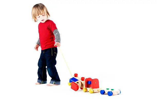 Photo of Adorable boy pulling a toy wooden train