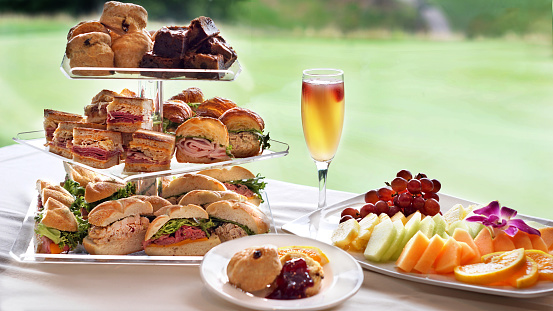 Afternoon Tea Party setting.  Finger sandwiches, scones, and brownies.  Fresh fruits and a glass of champagne.