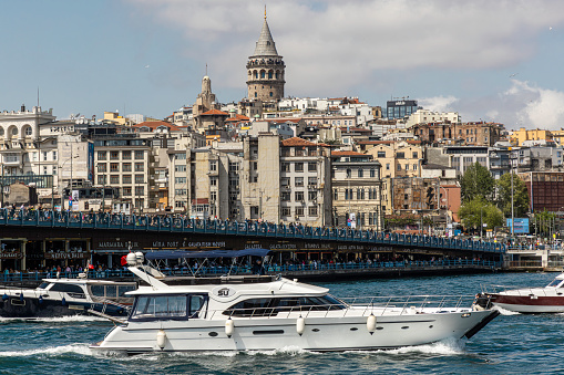 Boat sailing in Bosphorus Strait, with the Istanbul skyline in the background, overlooking Galata Bridge with traditional fish restaurants and Galata Tower, Istanbul, Turkey