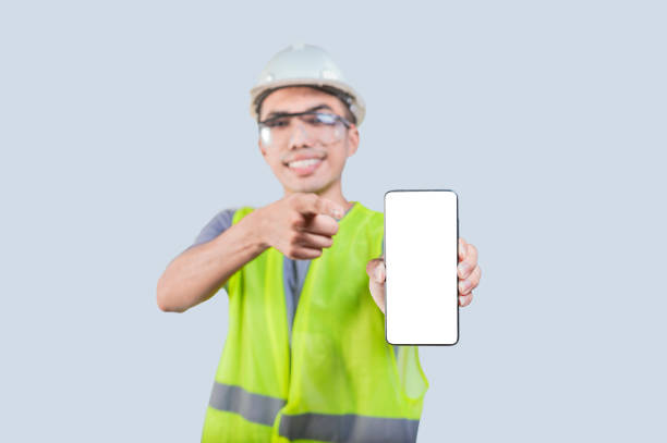 istock Engineer holding out the phone showing advertising on blank cell phone screen. Engineer points to blank mobile phone screen 1521157609