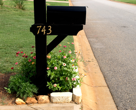 A  black  rural mailbox with the flag raised and copy space on blank  envelopes in the mailbox. Isolated on a white background.