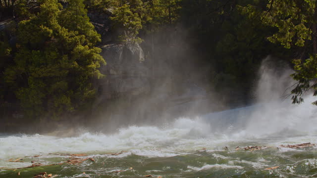 Mist and powerful flowing water from rushing river and flooding in Yosemite National Park