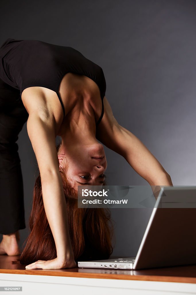 Kobieta w pozycji jogi koło Patrząc na laptopa. - Zbiór zdjęć royalty-free (Czarny kolor)