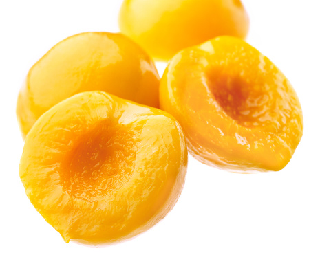 A group of canned peach halves on syrup, over white background