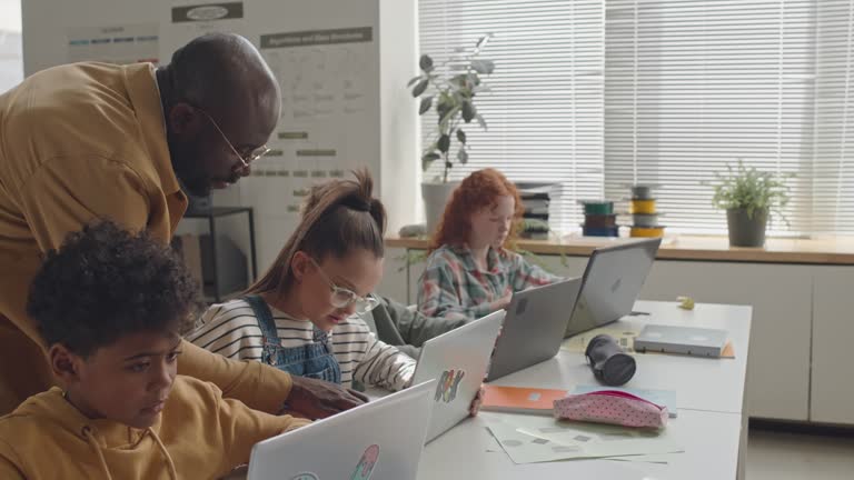 School Kids Learning Programming with Help of Male Teacher