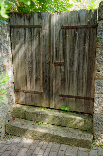 istock grey weathered wooden gate on a stone wall, double-winged 1521224564