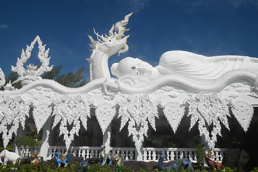 Large white outdoor reclining Buddha enshrined under the protection of the Serpent at Wat  Don Khanak for peoples travel to pay homage to the holy things. Located at Nakhon Pathom Province in Middle of Thailand.