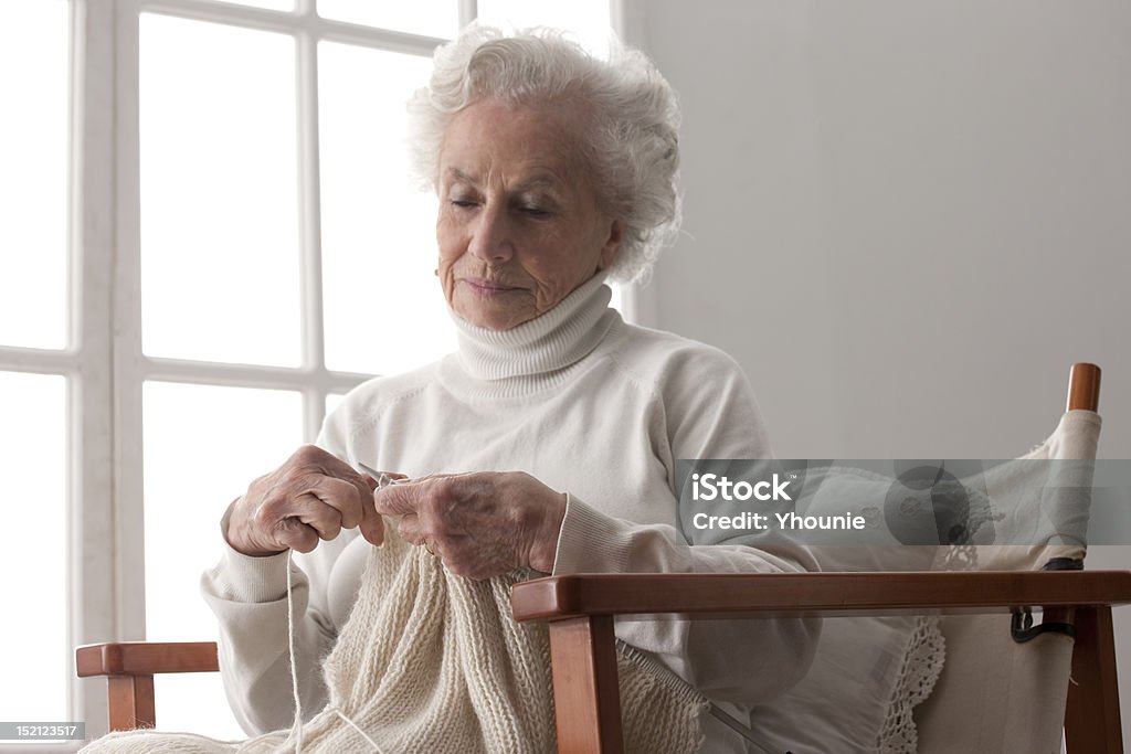Senior woman knitting Old woman knitting beside window Grandmother Stock Photo