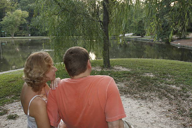 young adults looking on a pond stock photo