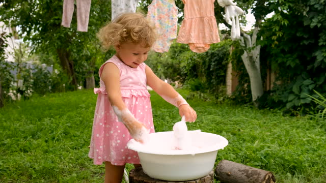 The child is washing clothes in the garden. Selective focus. Kid.