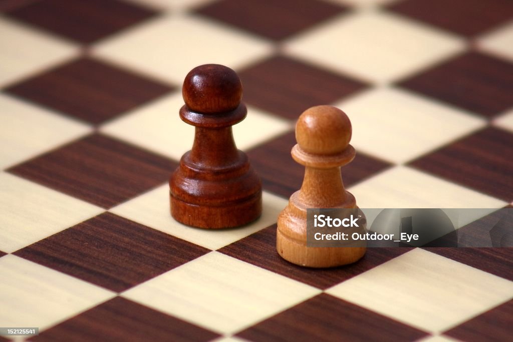 Confrontation on a checkerboard Two peasants on a wooden checkerboard Aggression Stock Photo