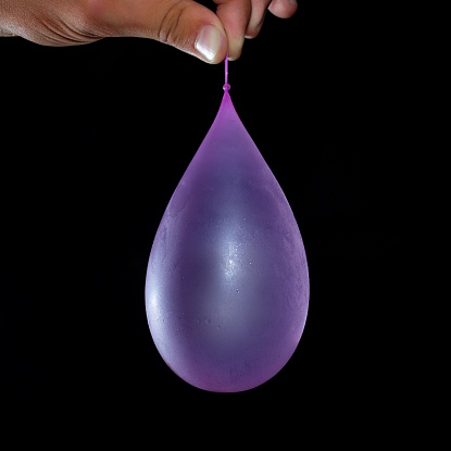 A purple water balloon is held in front of a black background.