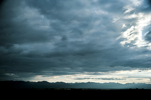View of mountain ridge on horizon under cloudy sky at dawn