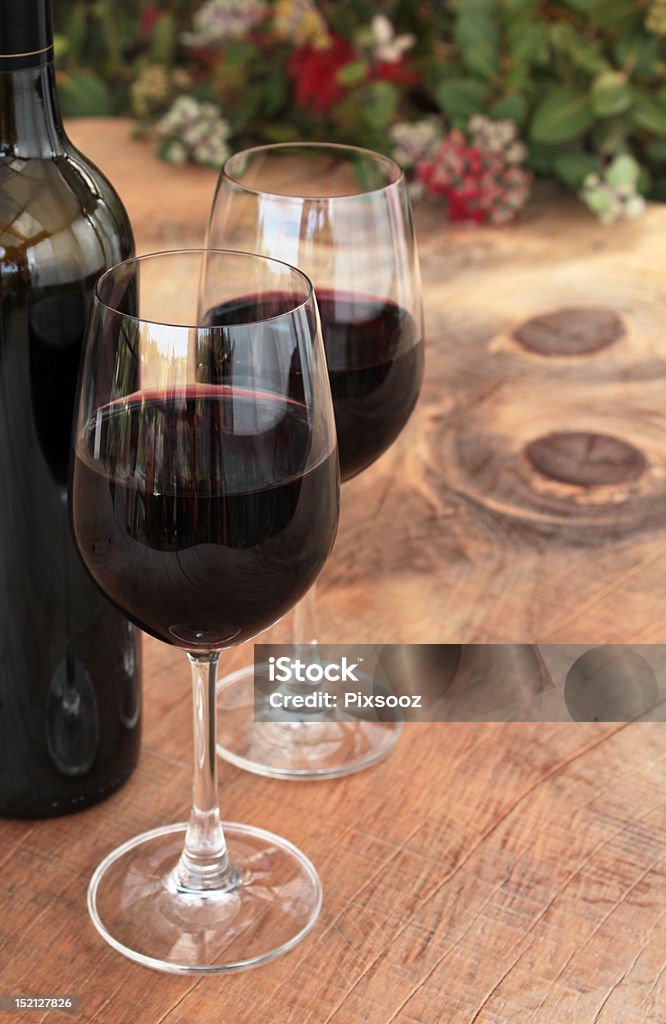 Garrafa de vinho & copos em uma mesa ao ar livre com Pohutukawa - Foto de stock de Arbusto royalty-free