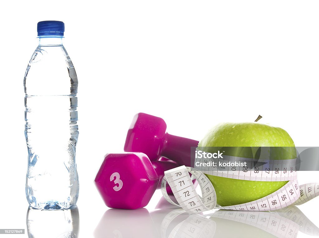 Mancuernas con manzana y cinta métrica alrededor de botella - Foto de stock de Agua libre de derechos