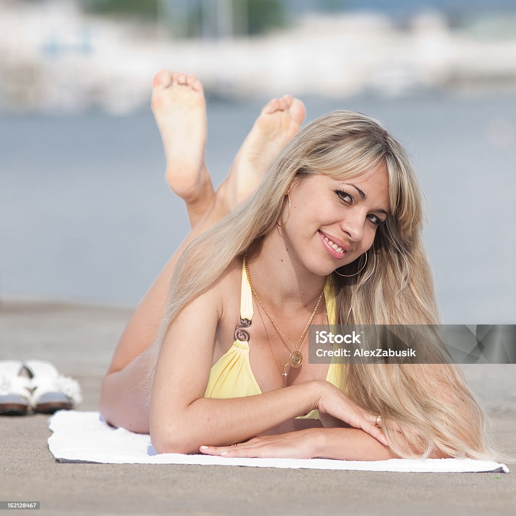Girl at the sea Attractive young woman in yellow swimsuit lying on the pier Seductive Women Stock Photo