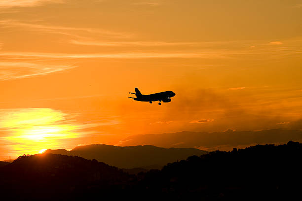 istock landing airplane silhouetted on orange sunset skies 152129816