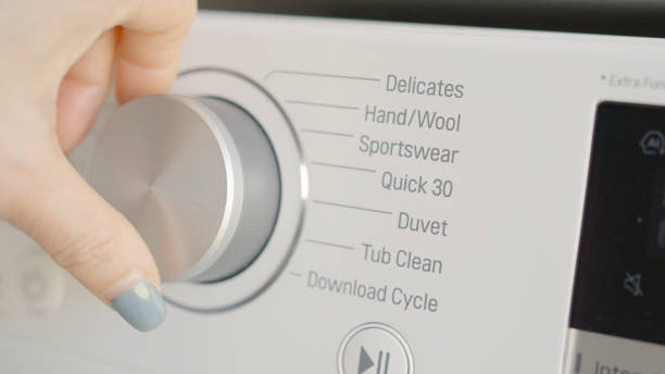 Woman hands turning washing machine dial to quick washing mode, energy saving concept