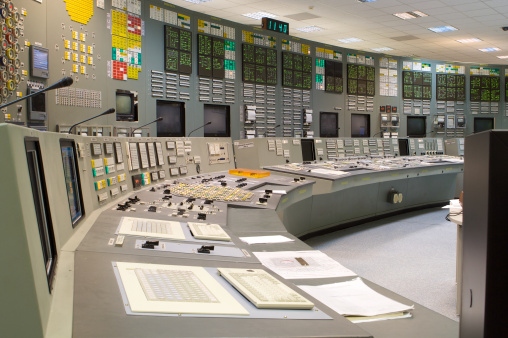 Back View in the System Control Center Operator Working. Multiple Screens Showing Technical Data.