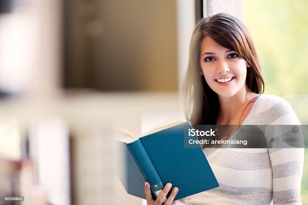 A college student of mixed race holding a blue book A portrait of a mixed race college student at campus University Student Stock Photo