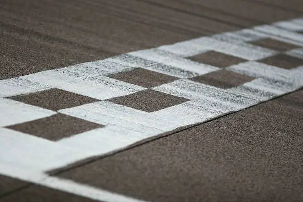 The painted start/finish line across the track at the Rockingham motor speedway in Northamptonshire, UK. Black tire marks are streaked across the track.