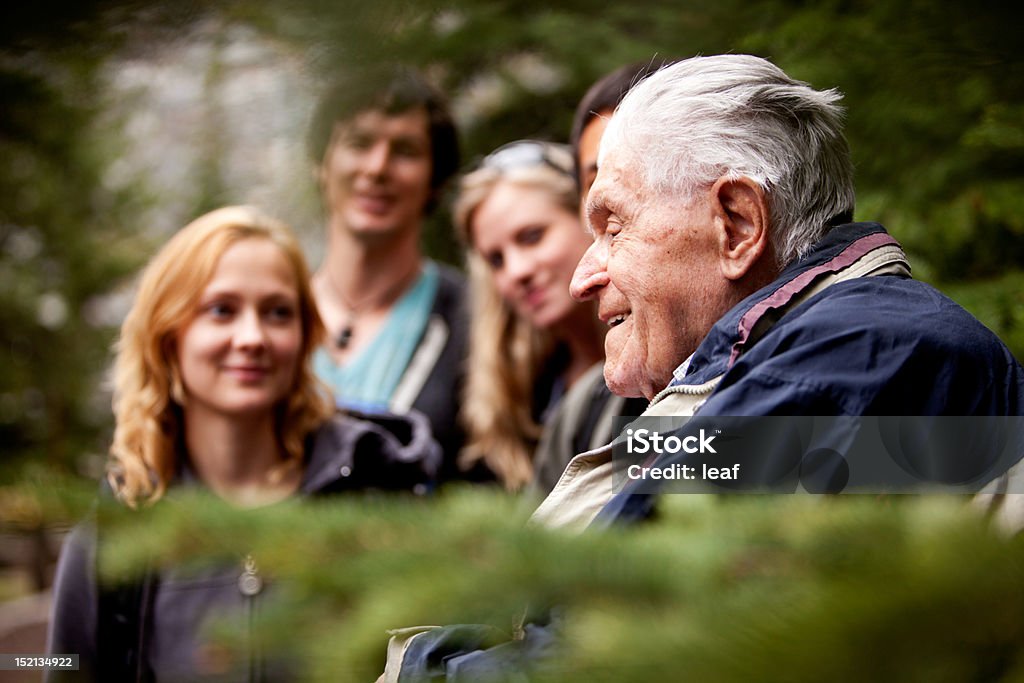 Elderly Man Group An elderly man telling stories to a group of young people Multi-Generation Family Stock Photo