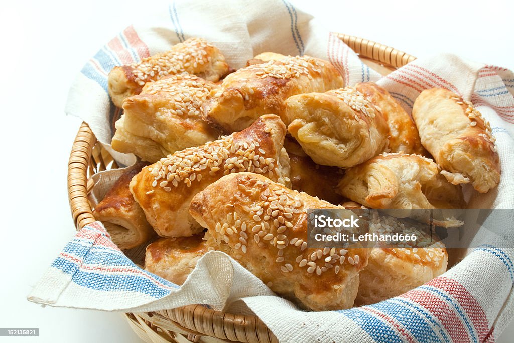 puff pastry patties Freshly baked patties from puff pastry filled with cheese sprinkled with sesame seeds arranged in a wicker basket close-up isolated on white background. Appetizer Stock Photo