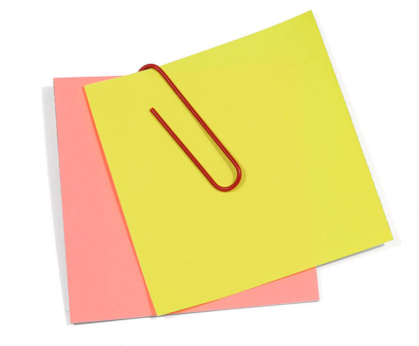 Blank yellow and pink sticky notes with a red paperclip stock photo