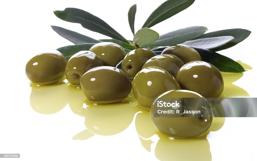 olives green olives lie in olive oil, in the background an olive branch Antipasto Stock Photo