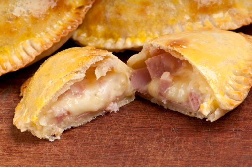 Ham and Cheese Empanada fill close up.  The Empanada is a pastry turnover filled with a variety of savory ingredients and baked or fried. In some Latin American cultures, the empanada is considered an appetizer and is served before a meal.
