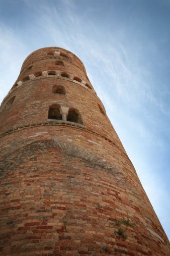 Medieval bell tower of St. Stephen Cathedral in blue sky with cirrus clouds in Caorle, Italy