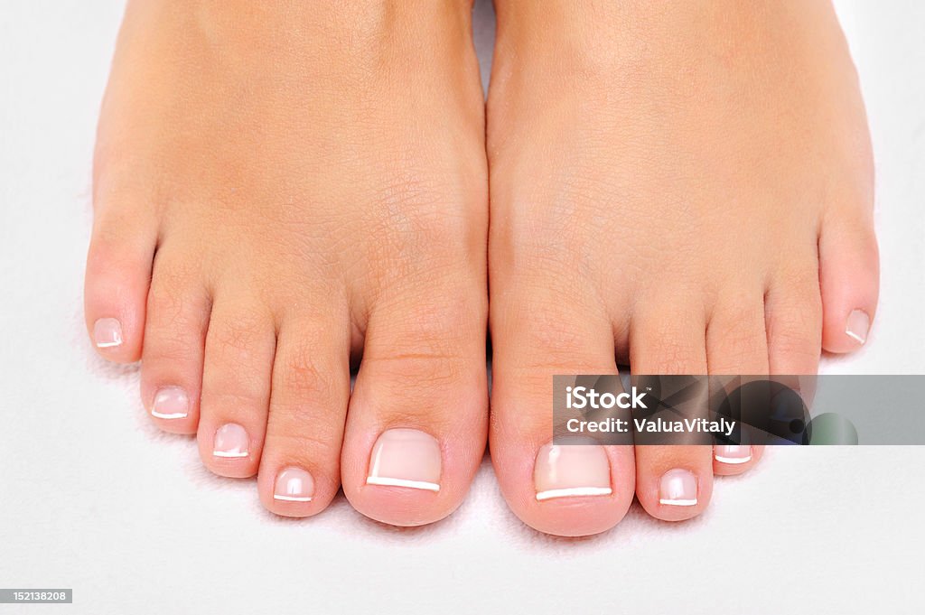 Beautiful female feet with French pedicure closeup Beautiful well-groomed female feet with the French pedicure Beauty Stock Photo