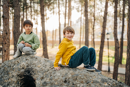 School boys kids playing travel outside in the forest. Siblings brothers children taking a hike in the rocky boulder forest city park.