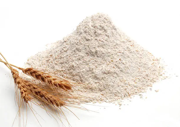 Whole flour and wheat ears on white background